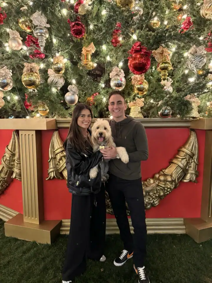 Couple from Los Angeles holding their Doodle in front of a Christmas Tree