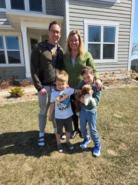Happy family picking up their Goldendoodle