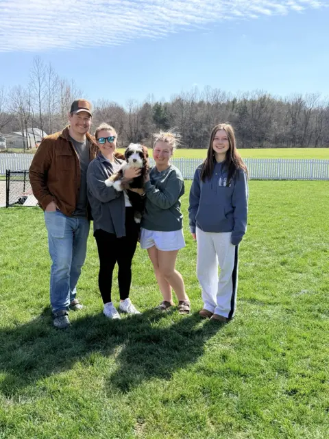 Family taking their first picture with the newest member, their Bernedoodle.