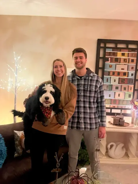 Young couple and their family photo with their Bernedoodle.