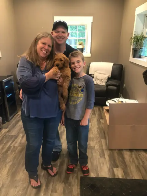 A family of three excited to take their new Goldendoodle home.