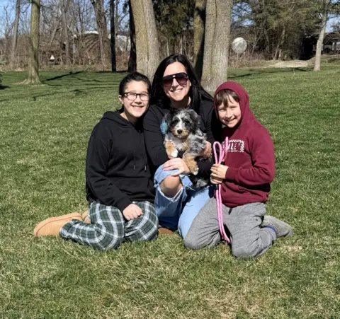 Mom and two siblings taking family photos with their Bernedoodle.