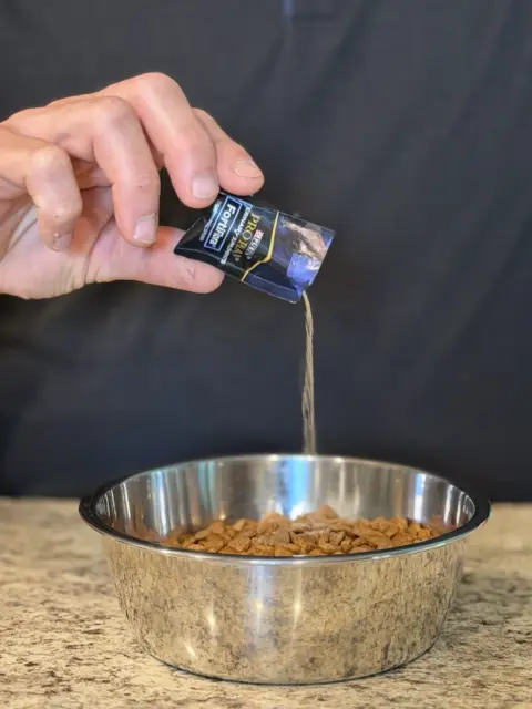Purina Pro Plan probiotic, getting dumped into a bowl of kibble dog food.