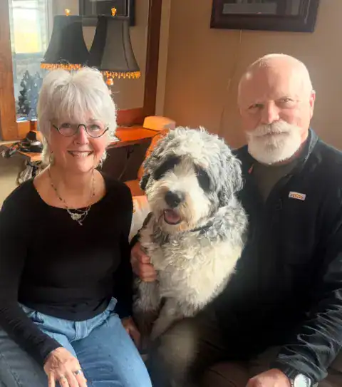 A Bernedoodle posing with his mom and dad for family photos