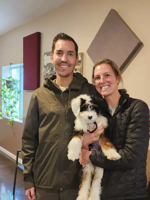 Happy parents and happy Bernedoodle after getting picked up from a training session