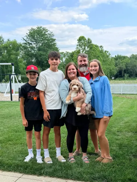 Happy family of five picking up their Bernedoodle.